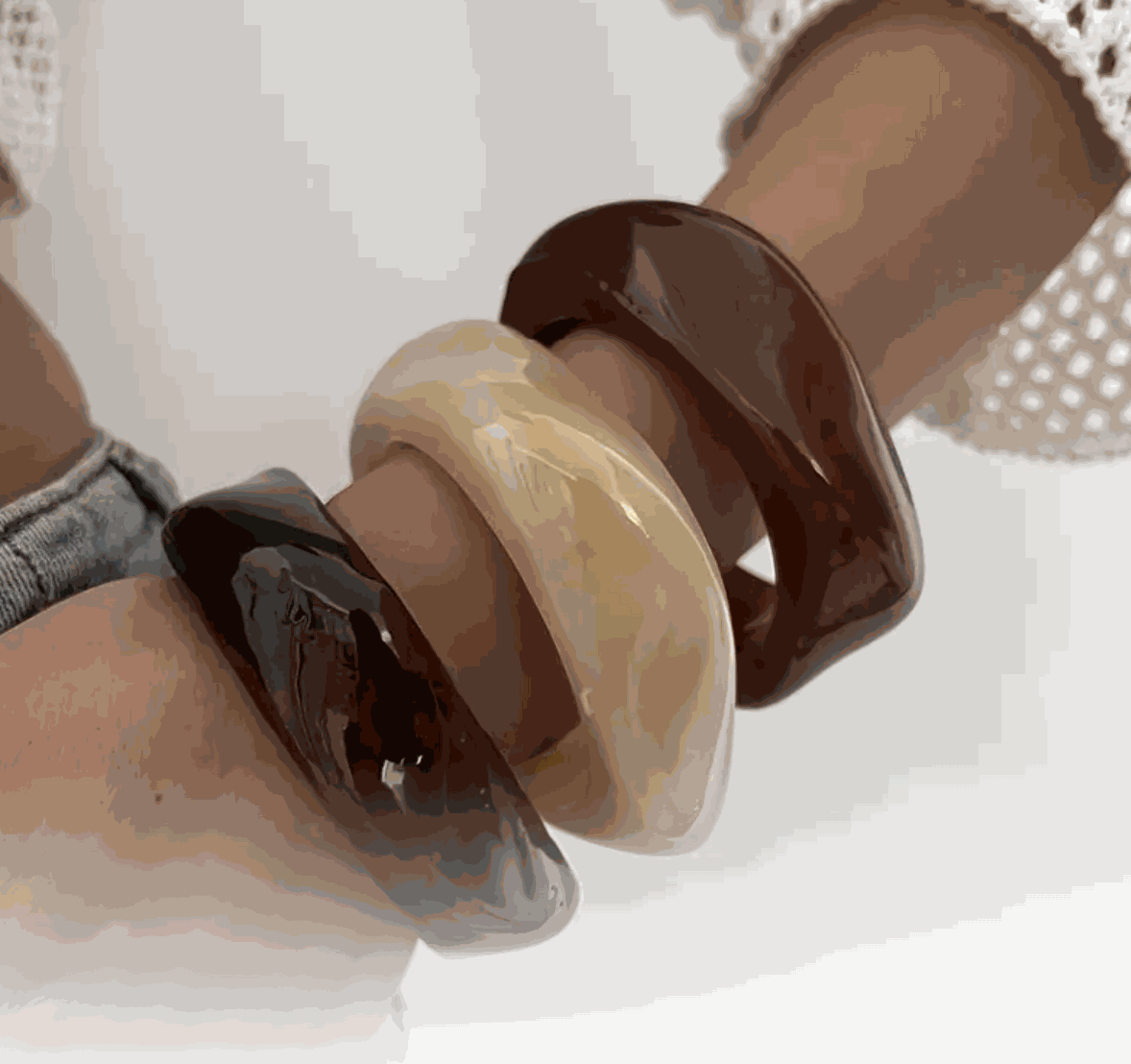 Molten Resin Wave Bangles in espresso brown, caramel beige, and deep amber stacked on a wrist.