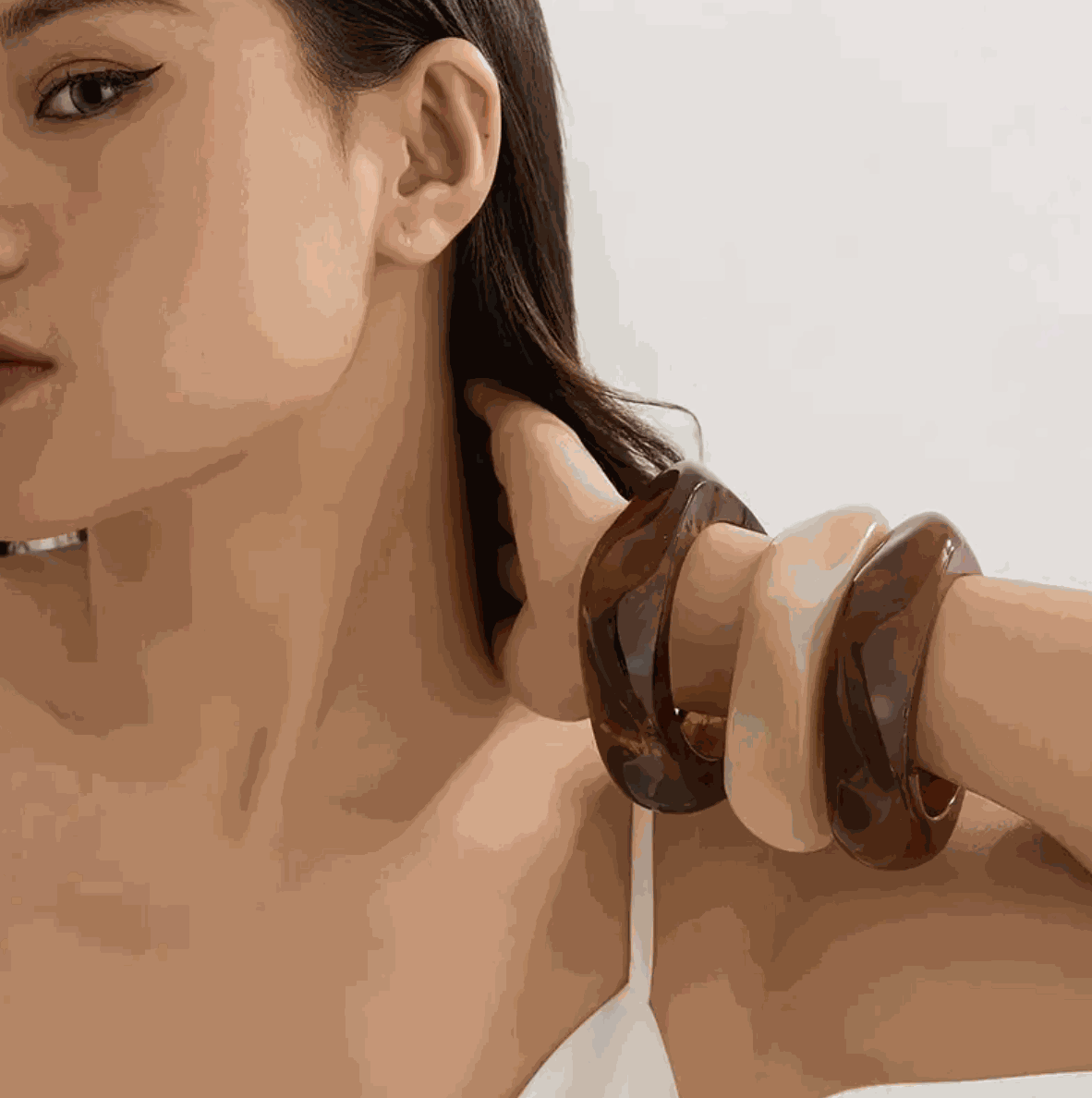 Model showcasing Molten Resin Wave Bangles in espresso brown and caramel beige, adding a chic accessory touch.